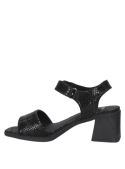Sandalia negra de cuero para mujer con banda ancha y patrón geométrico, ideal con jeans o vestidos.