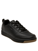 Zapatilla negra unisex de estilo colegial, corte bajo y aspecto elegante, ideal para combinar con jeans o ropa casual.