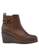 Botín chelsea de mujer en cuero café con suela de cuña, estilo casual y urbano, con aplicación metálica decorativa.