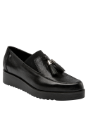 Zapato mocasín negro de mujer en cuero con suela gruesa y borlas decorativas, ideal para un look casual sofisticado.