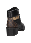 Botín negro de cuero femenino, combina robustez y elegancia con su diseño de combate y patrón decorativo trasero.