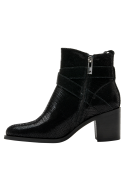 Botín de cuero negro con detalle de correa cruzada y hebilla metálica, patrón reptil en tendencia urbana chic.