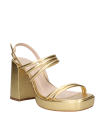Calzado femenino dorado de cuero, tiras cruzadas y taco grueso, versátil para looks casuales y elegantes.