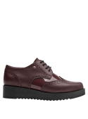 Zapato de mujer burdeo tipo oxford en cuero con detalles brogue, suela gruesa y diseño moderno que mantiene un aire clásico.