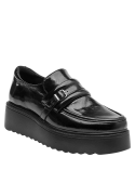Zapato de mujer en cuero negro, tipo mocasín, con hebilla decorativa y suela gruesa tipo plataforma.