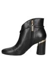 Elegante botín de cuero negro para mujer, con correa decorativa y adorno metálico que realza su diseño asimétrico.