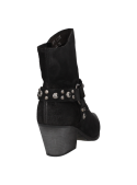 Botín estilo western de cuero negro, correa con tachas alrededor del tobillo, mezcla de modernidad y rusticidad.