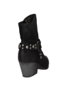 Botín estilo western de cuero negro, correa con tachas alrededor del tobillo, mezcla de modernidad y rusticidad.