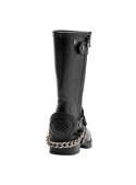 Bota motera negra de cuero con detalles metálicos, ideal para conciertos o paseos, combina robustez con sofisticación.