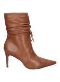 Detalles de cordones decorativos en el tobillo, complementan el estilo elegante y sofisticado del botín de cuero camel.