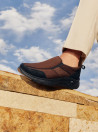 Zapatilla marrón de cuero estilo mocasín urbano para hombre, sin cordones, material gamuza elegante y casual.