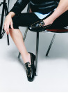 zapato mocasín negro de cuero para mujer con adorno metálico en el empeine y tachas decorativas en el borde superior