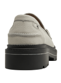 Mocasín beige de cuero para mujer con adorno metálico elegante y suela negra robusta.