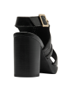 Elegante sandalia de cuero negro con acabado brillante, perforaciones y hebilla dorada.