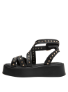 Sandalia negra de cuero con plataforma y tiras cruzadas, hebilla dorada ajustable para un look urbano.