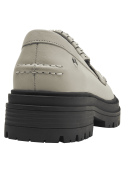 Mocasín de cuero beige para mujer con tachas metálicas en el empeine y flecos, estilo casual y moderno.