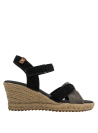 Sandalia de mujer con cuña de yute y tiras cruzadas, combinando cuero negro y texturas contrastantes.