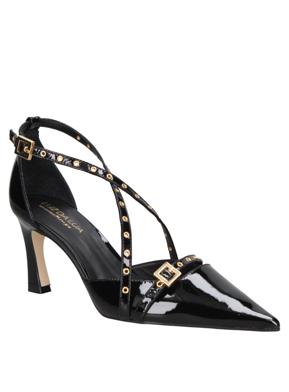 zapato de mujer en charol negro con un acabado brillante y correas decorativas con ojales dorados.