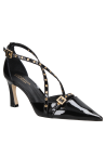 zapato de mujer en charol negro con un acabado brillante y correas decorativas con ojales dorados.