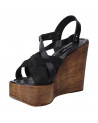Calzado casual de mujer en cuero negro, sandalia con plataforma y cuña, ideal para ocasiones informales.